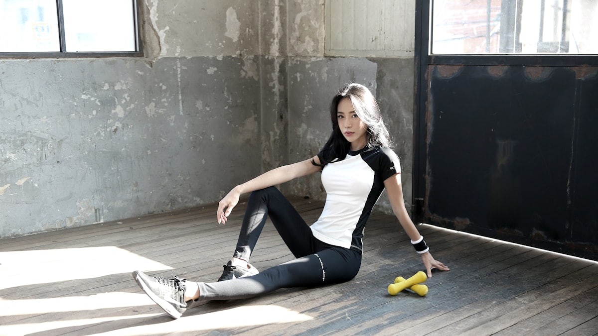 woman in black tank top and black leggings sitting on floor